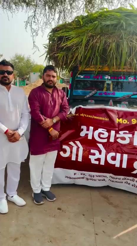 Trust volunteers holding the Mahakal Gau Seva Trust banner in front of a tractor-trolley loaded with green fodder